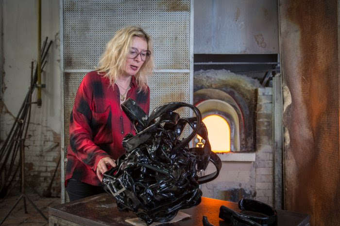 The Glasstress furnace in Venice blazes behind the artist Monica Bonvicini as she works on her glass sculpture Bonded.